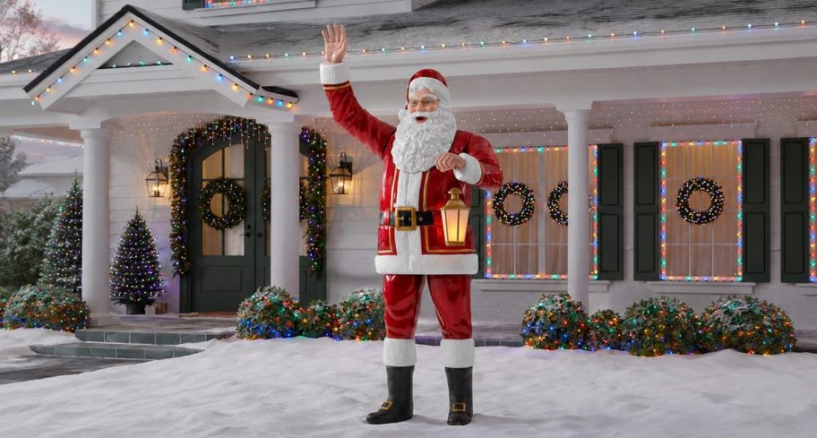 Giant lighted Santa holding a lantern outside a decorated home