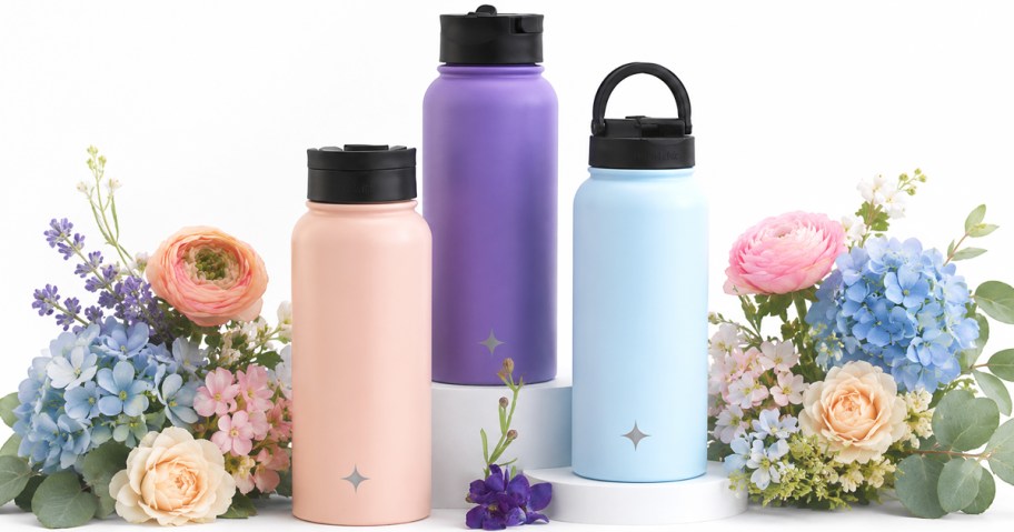 pink, purple, and blue water bottles surrounded by flowers