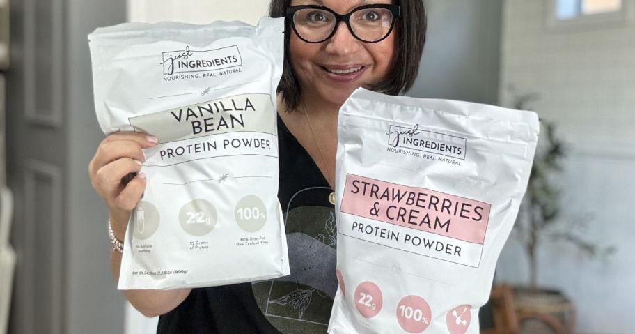 Woman holding two large bags of Just Ingredients Vanilla and Strawberry & Cream protein powder
