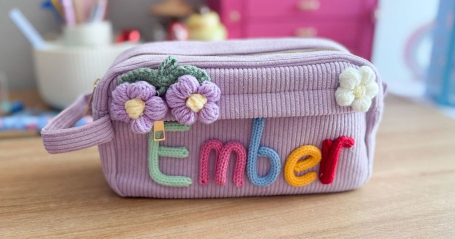 purple KEQHAULI Custom Corduroy Pencil Case with "Ember" embroidered on it on desk
