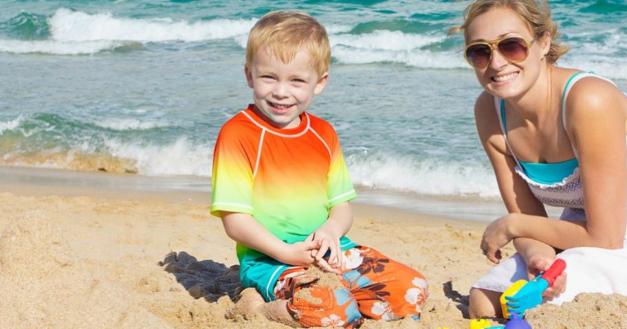 Little Boy Wearing a rash guard on a beach with a woman
