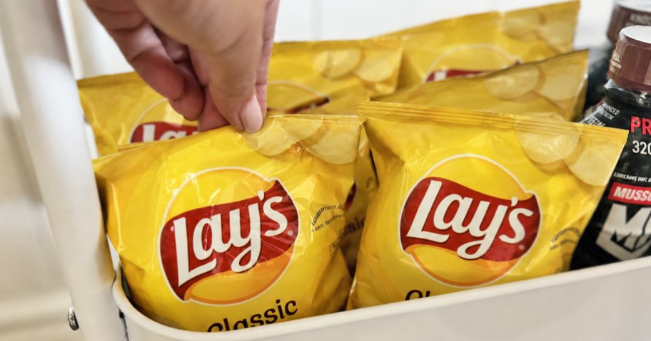 hand grabbing yellow back of chips from a snack cart