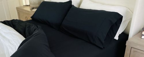 A bed with black Linens & Hutch Essential Sheets
