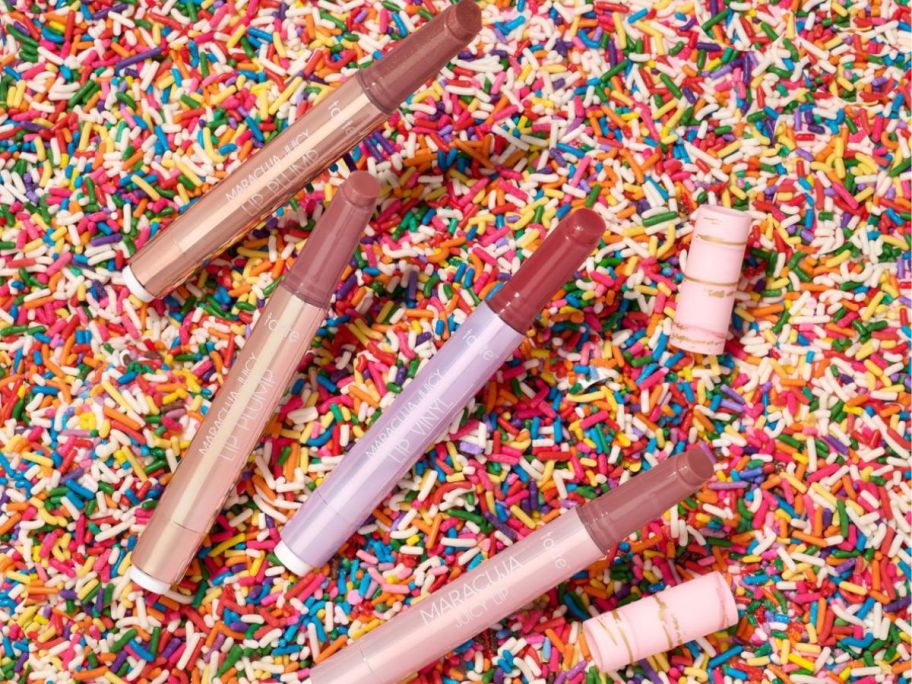 tarte MJL lip plumpers in vanilla scents and mauve colors displayed on a bed of sprinkles