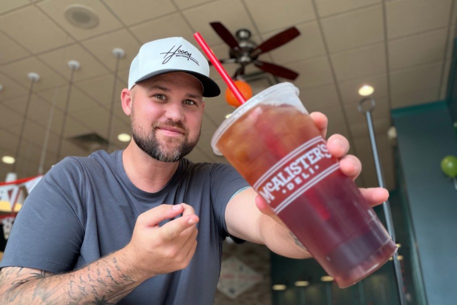 man holding up a McAlister's Deli Tea 