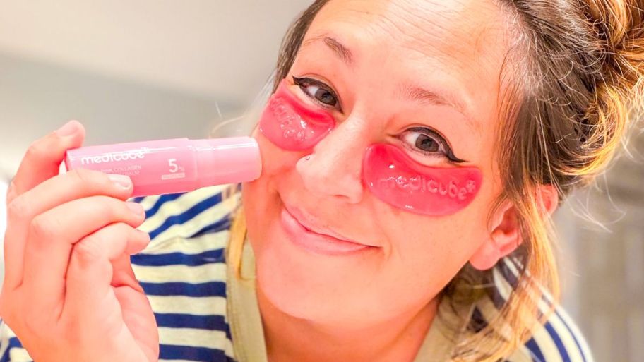 Woman apply Medicube collagen balm on her cheeks while wearing medicube eye patches