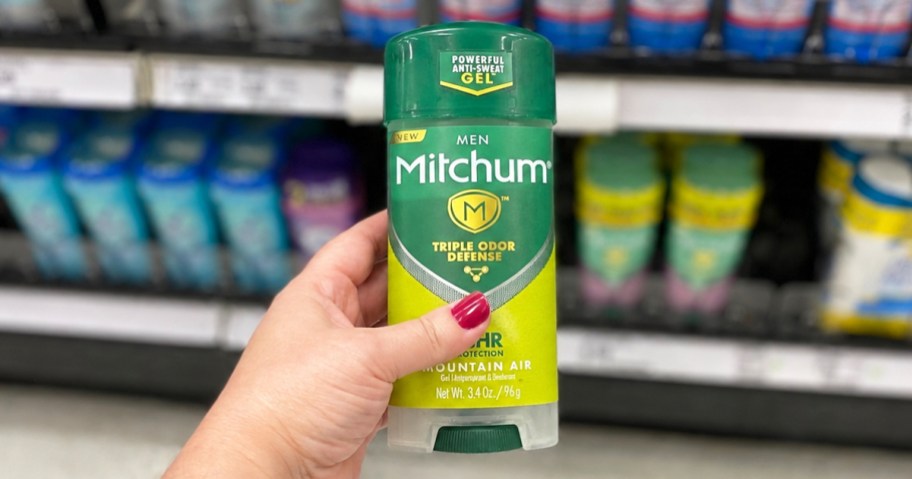 hand holding a stick of Mitchum Deodorant in store aisle