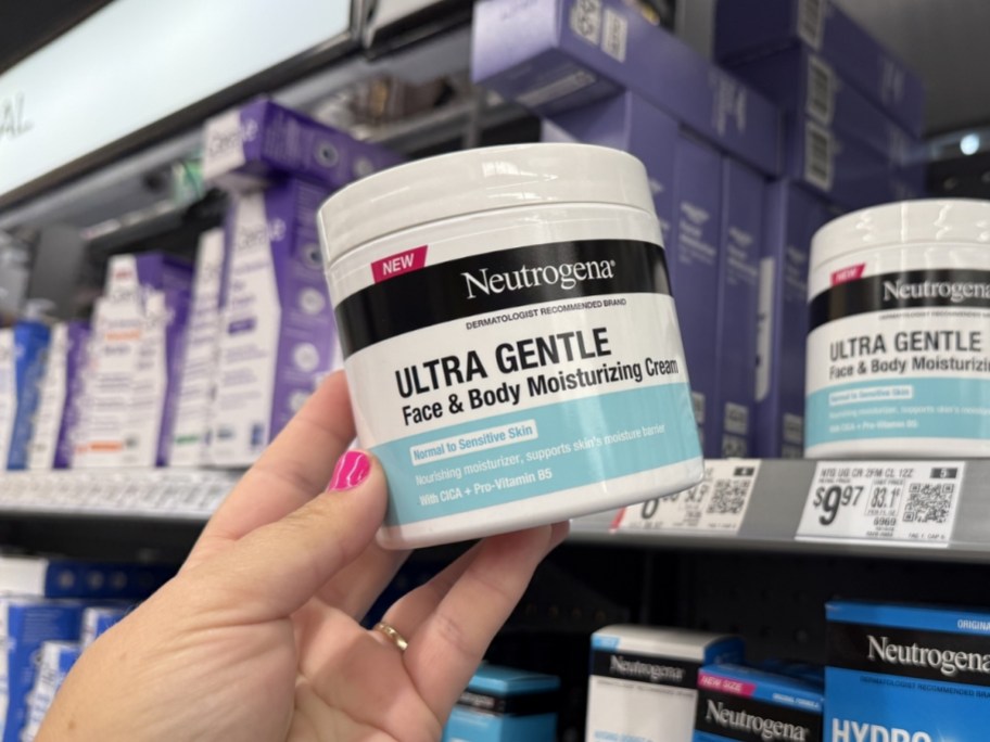 person holding Neutrogena Ultra Gentle Face & Body Cream 11oz container in walmart