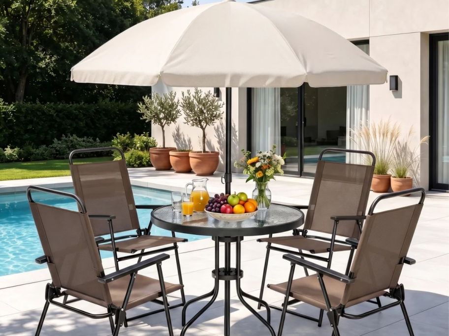 Outdoor seating with an umbrella and fruits on top of the table 