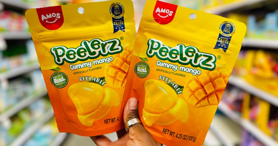 hand holding up two bags of Peelerz Mango Gummies in store aisle