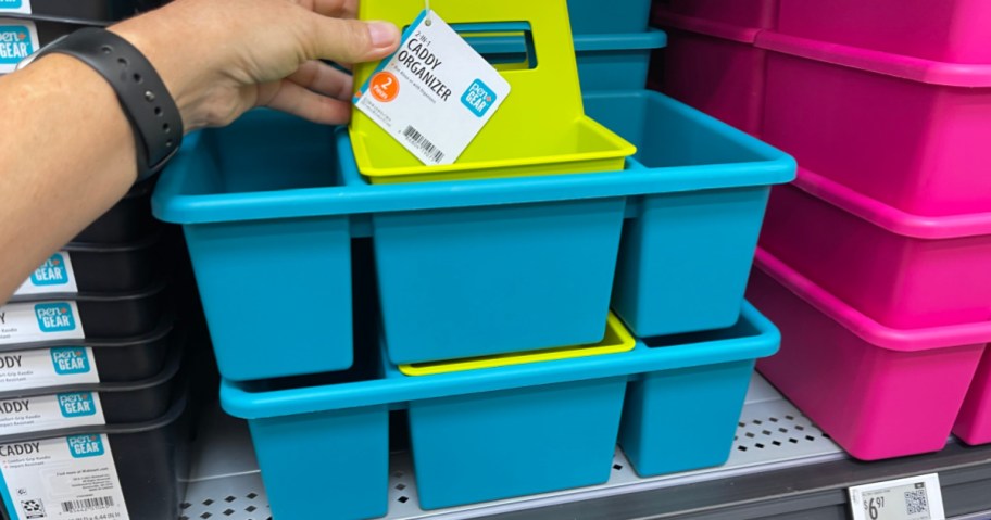 A hand holding a lime green Pen+Gear caddy organizer sitting inside a larger blue caddy on a store shelf.