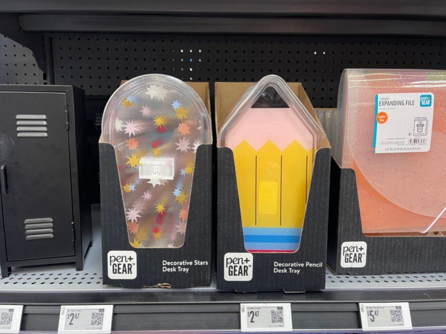 A Pen+Gear Decorative Pencil Desk Tray in its packaging on a store shelf, next to a star-patterned desk tray.
