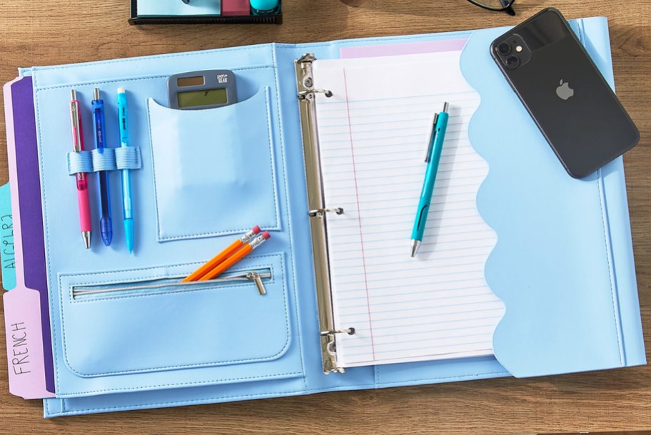 blue binder opened on table with pockets and binder paper inside