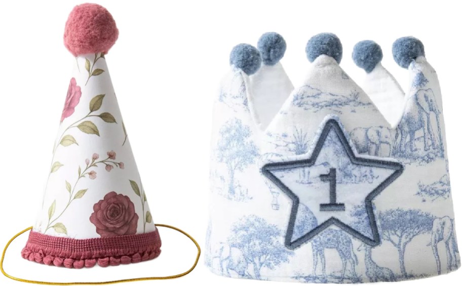 A pink floral party hat with a pink pom-pom next to a soft blue patterned birthday crown featuring a star with the number 1.