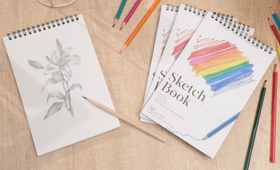 sketchbooks sitting on a table with colored pencils