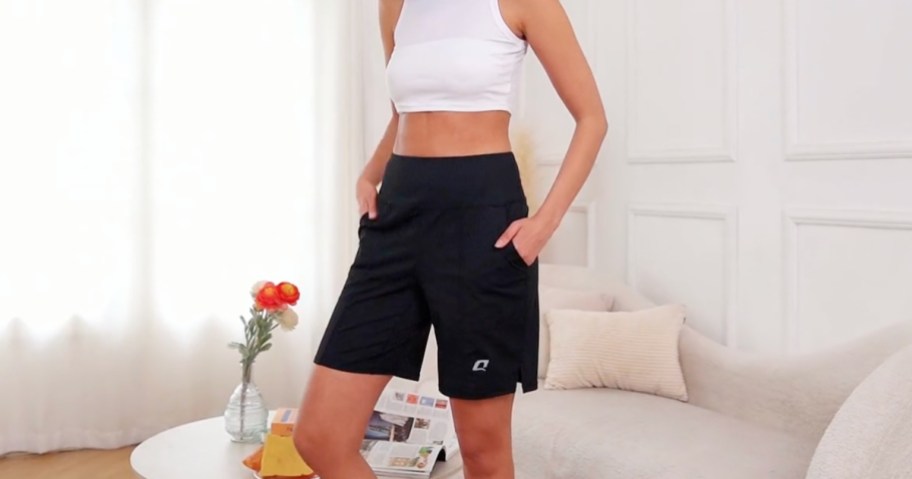 woman wearing black bermuda shorts and white tank top in living room