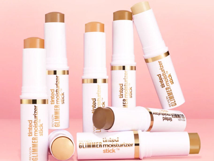 multiple tubes of Revlon Glimmer Tinted Moisturizer Sticks on a pink background