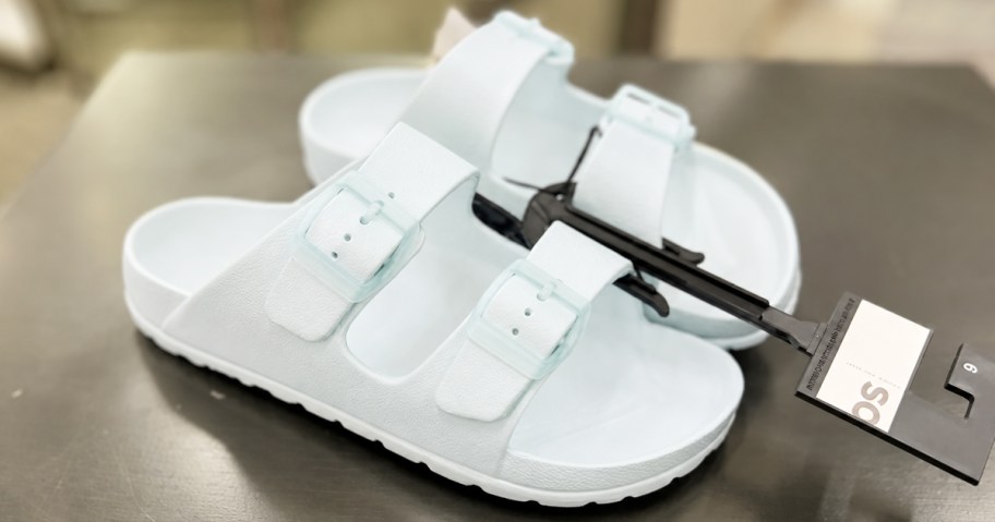 pair of light blue double buckle sandals on black table