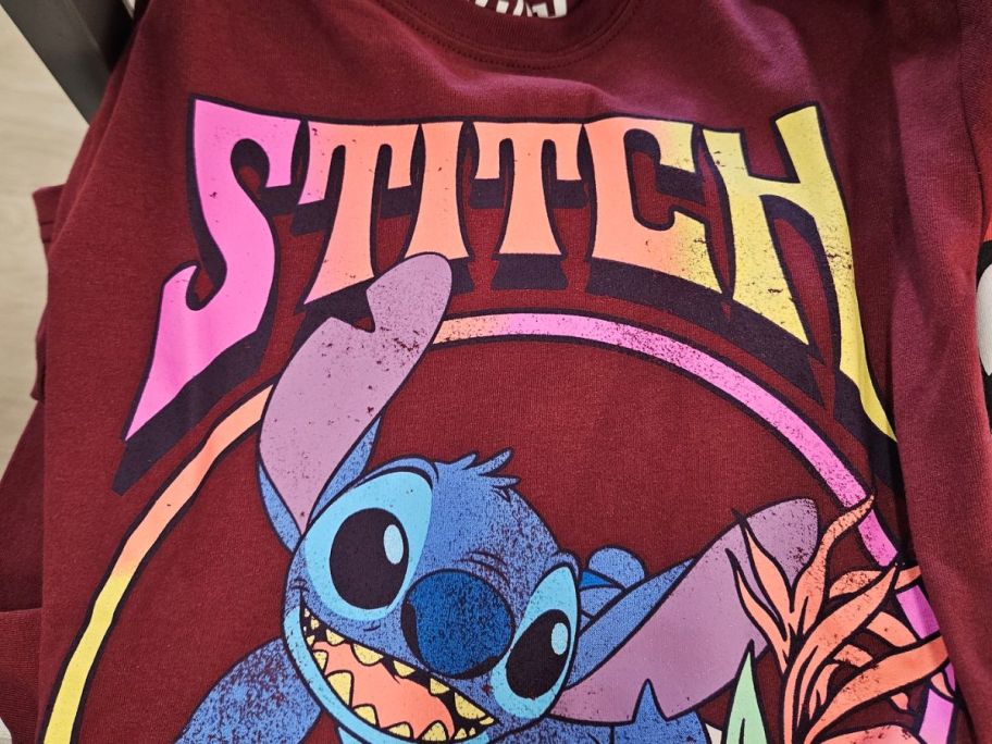 hand holding stitch graphic tee shirt with a burgundy colored design