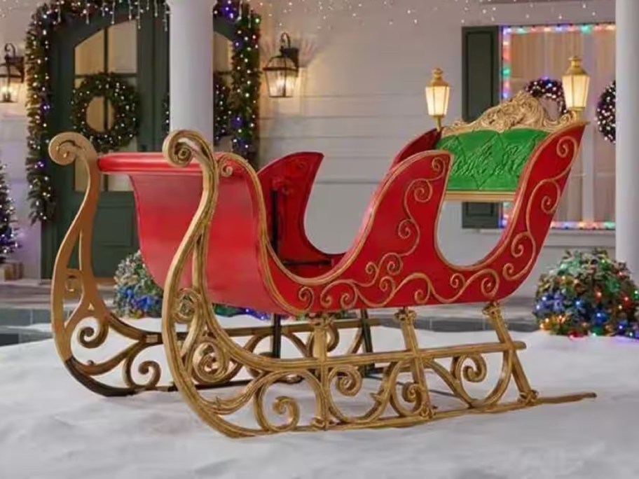 Giant red and gold Santa sleigh displayed in a snowy Christmas yard