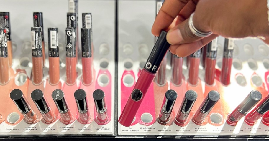hand holding up a pink tube of lip stain