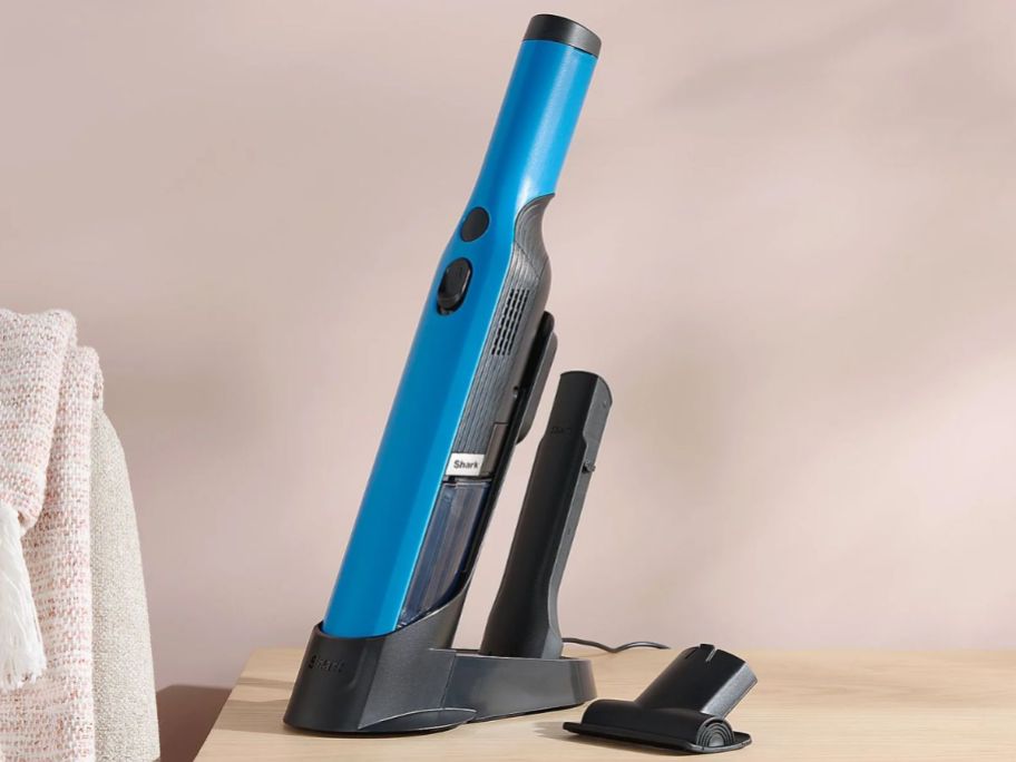 A bright blue Shark Wandvac on a nightstand
