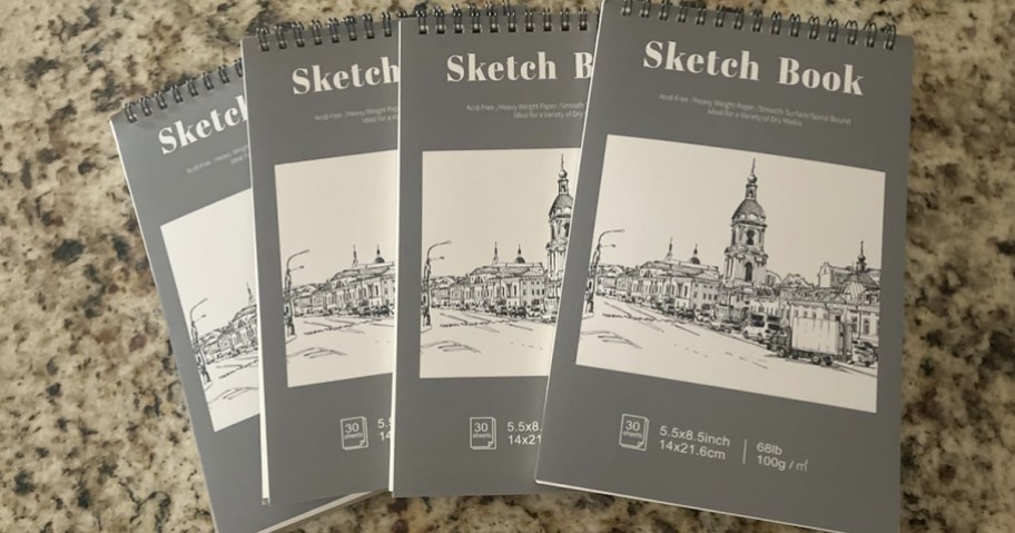 four sketch books laid on a granite counter