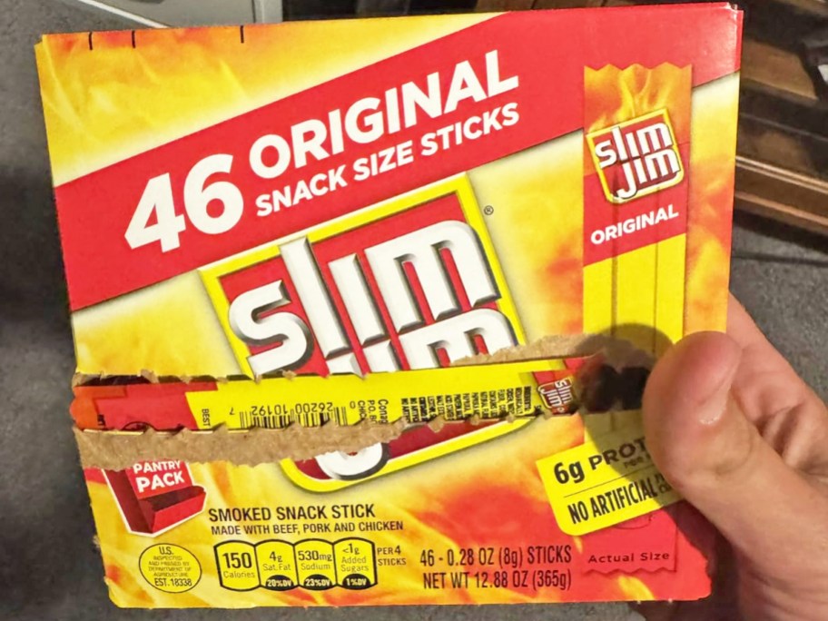 hand holding a yellow and red box of Slim Jim Snack Size Sticks