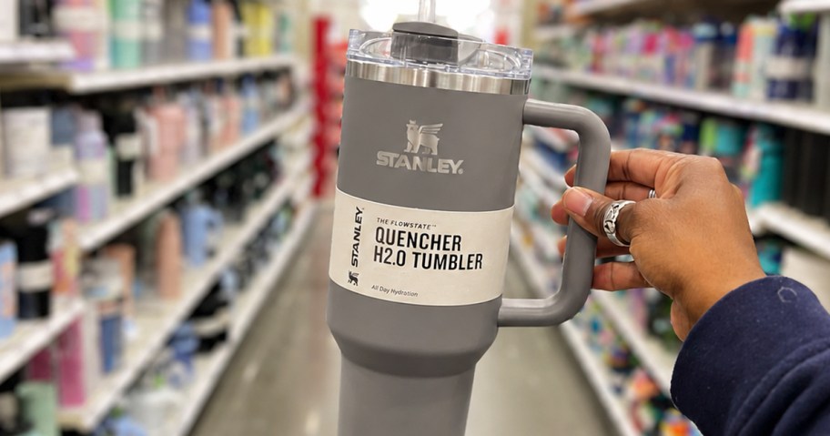 hand holding up a grey stanley tumbler in store aisle