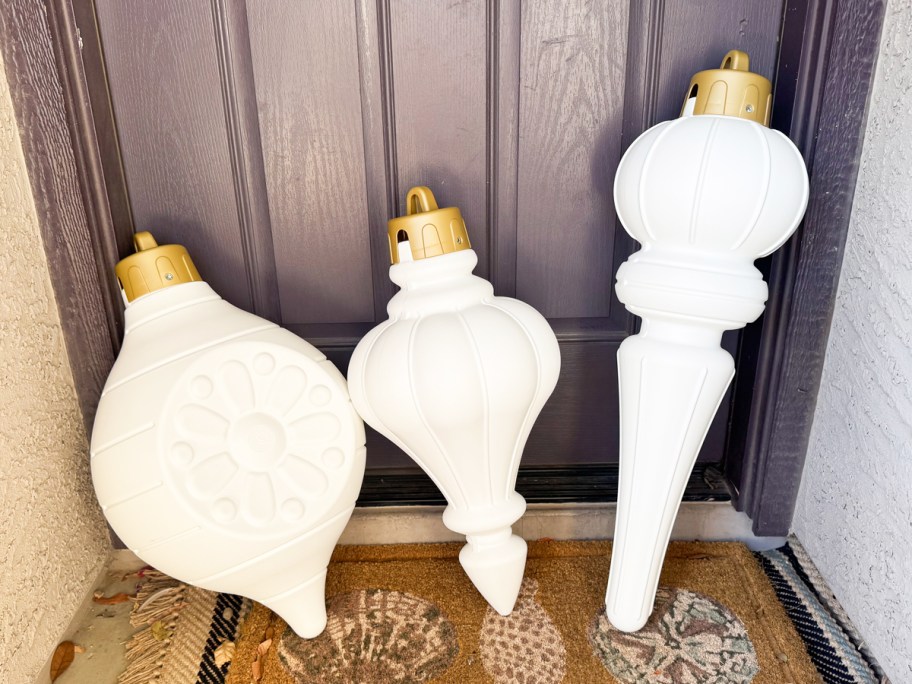 Three large white plastic ornaments leaning against the front door.