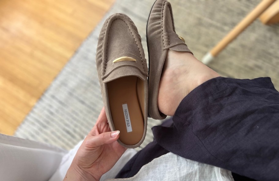 hand holding up steve madden suede mule shoe while wearing on feet
