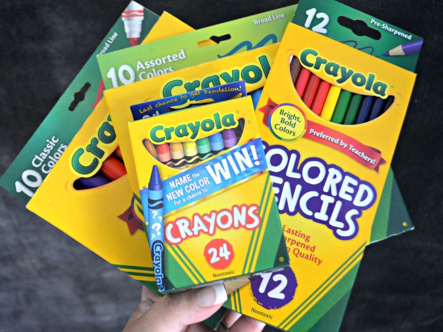 hand holding boxes of Crayola crayons markers and colored pencils