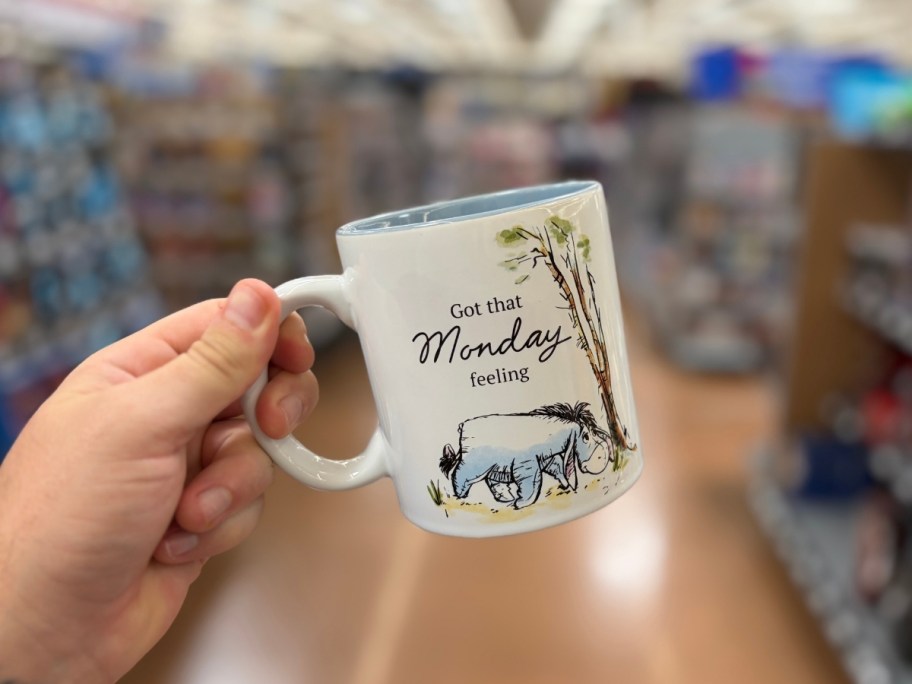a hand holding an eyore charater ceramic mug
