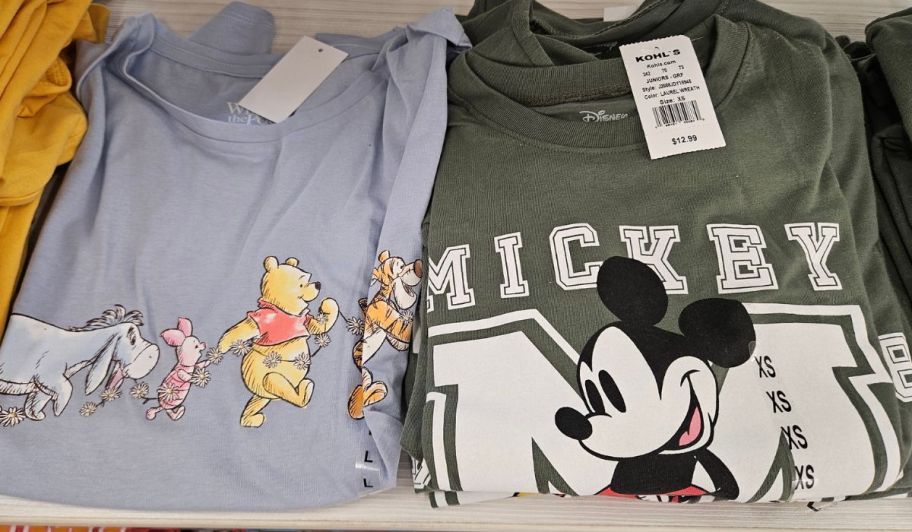 Winnie the pooh and mickey graphic tees displayed on a store shelf