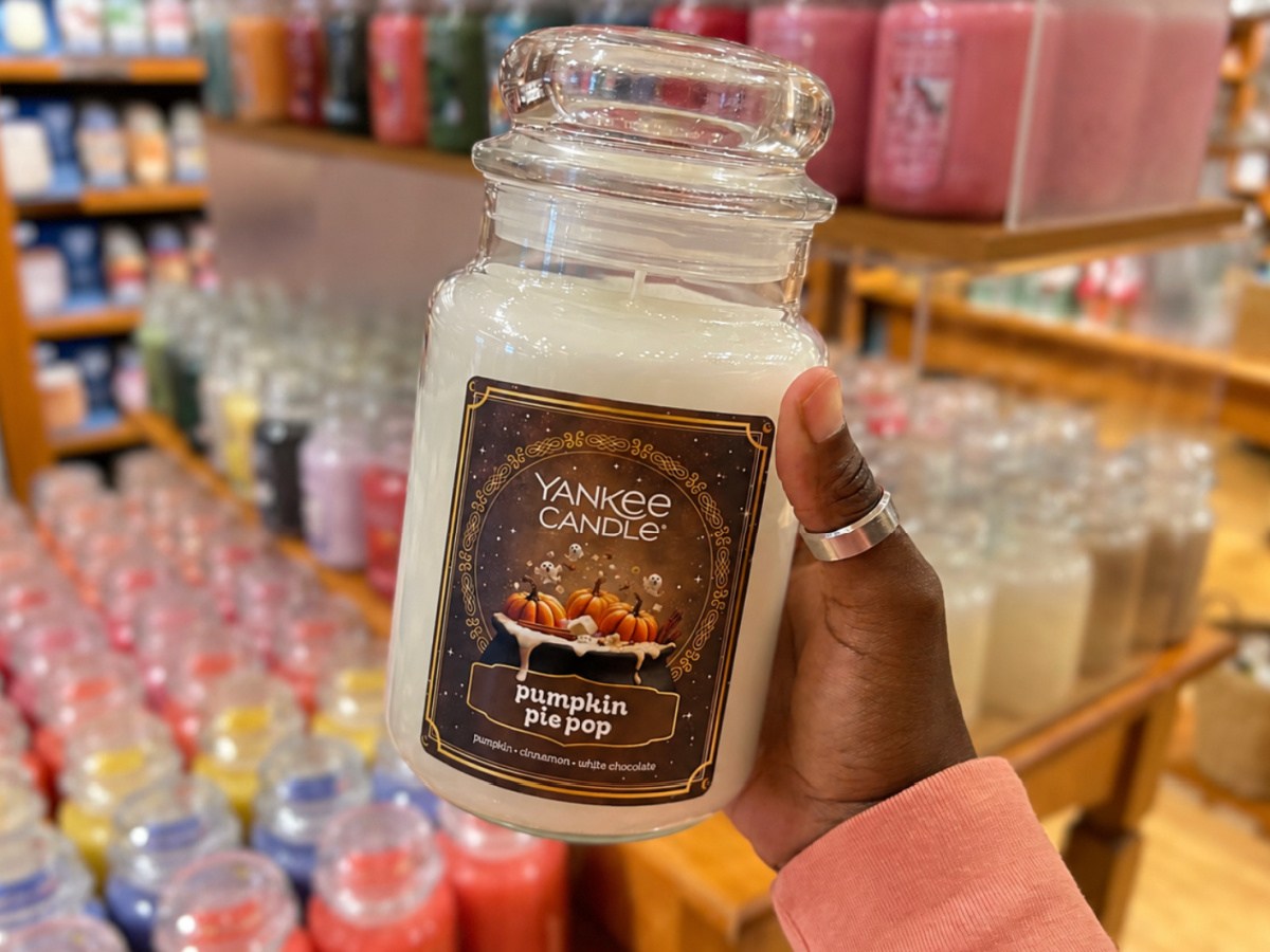 Hand holding Yankee candle, pumpkin pie pop inside store