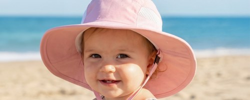 girl wearing pink sun hat at beach