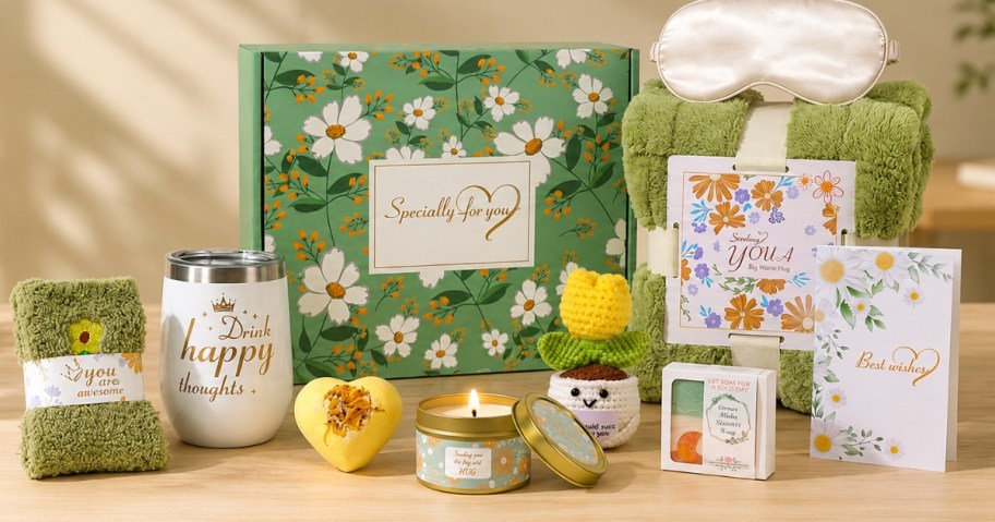 a gift box with various items around it included a blanket, socks, candle, and more