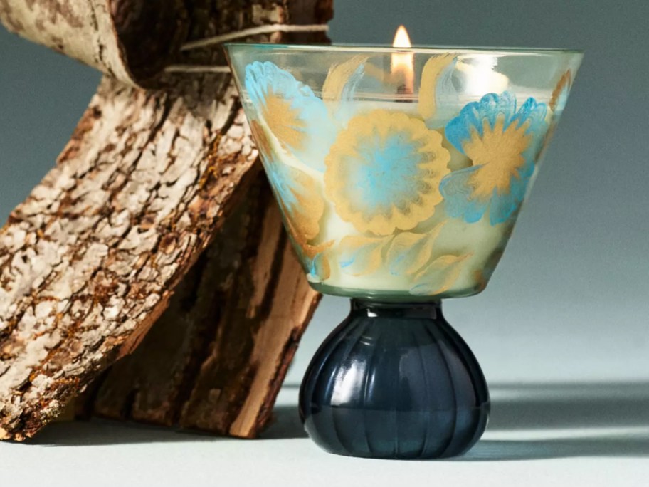 blue floral candle with wood behind it