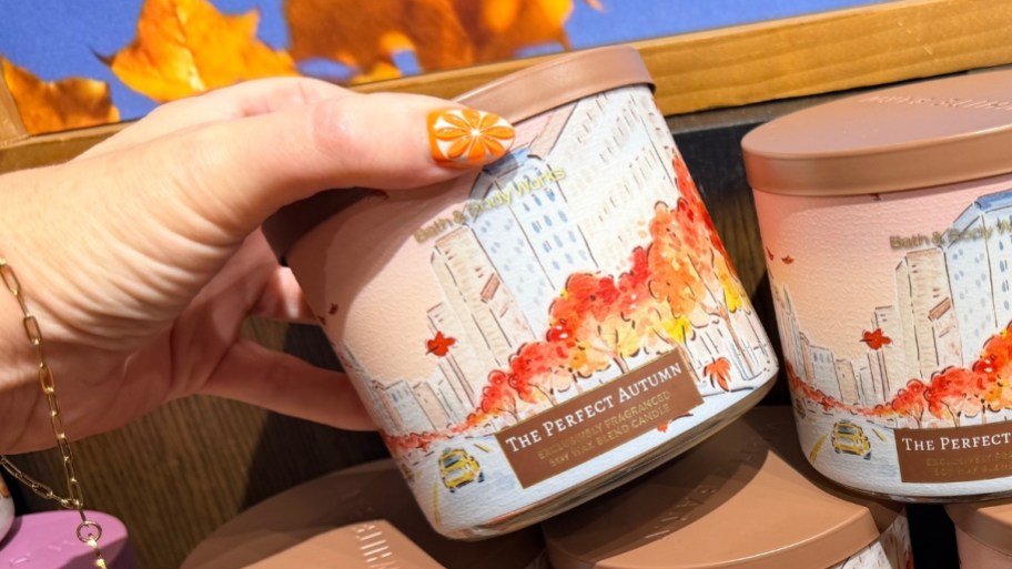 a hand holding a 3 wick candle