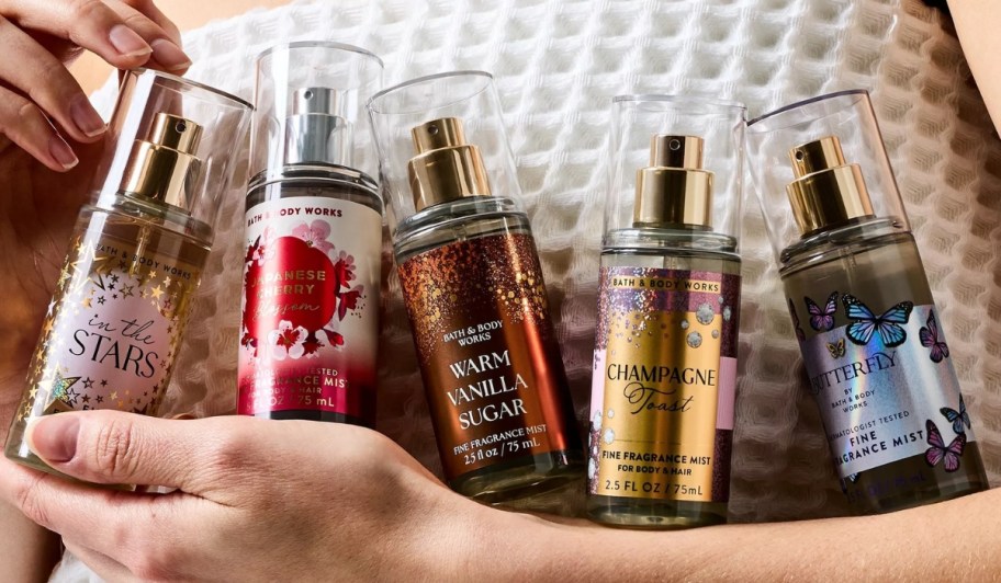 a woman holding 5 mini bottle of body mist