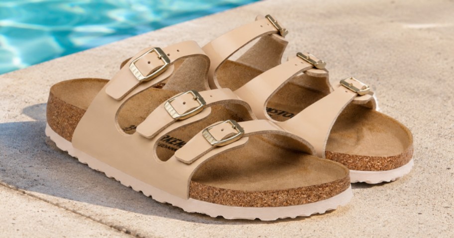a pair of tan Birkenstock sandals by a swimming pool