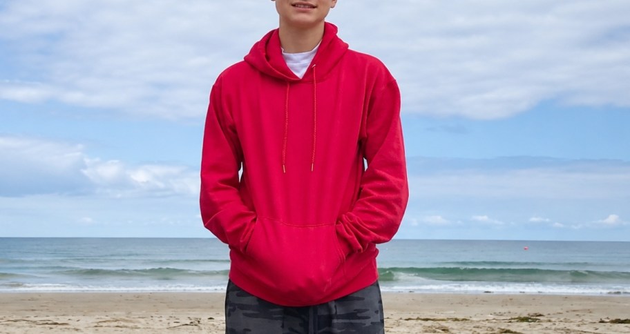 a man in a red hoodie on the beach