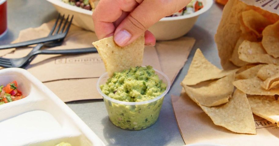 hand dipping chip into chipotle guac
