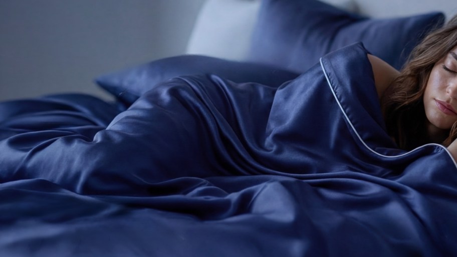 a woman under a dark blue cooling blanket