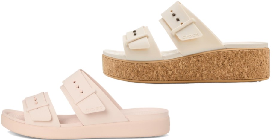 Two pairs of Crocs sandals with double-strap buckle designs featuring a light pink flat sandal and an off-white platform sandal with a cork-wrapped wedge sole.
