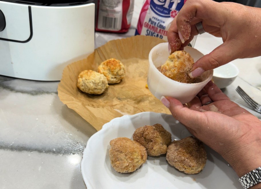 dipping donut hole in sugar and cinnamon
