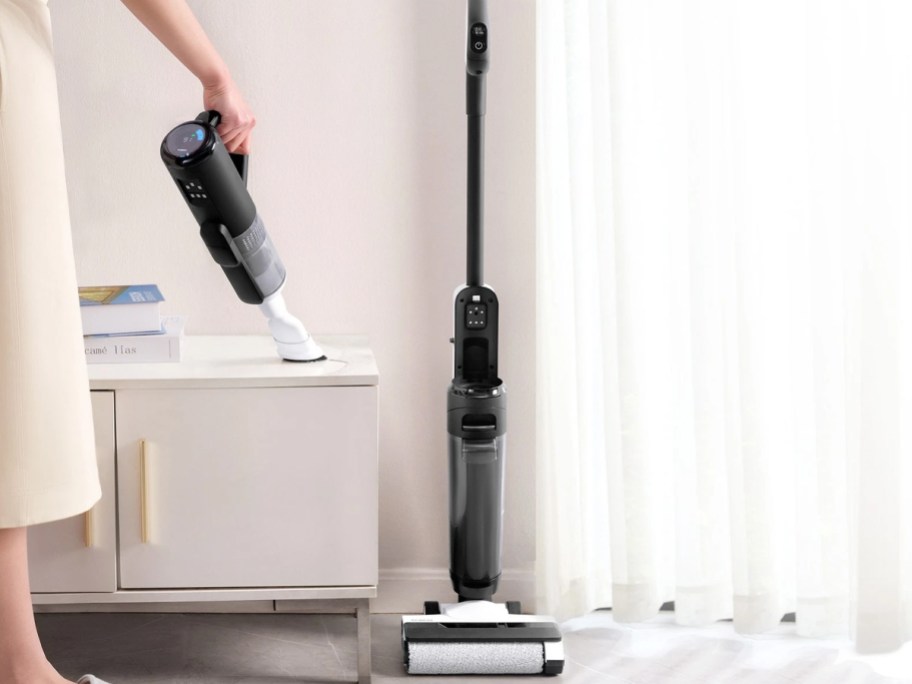 vacuum on charger and person using handheld vac
