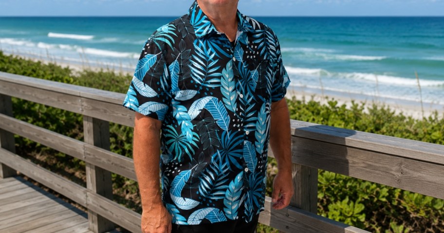 man earing a Hawaiian style shirt on a boardwalk by the ocean
