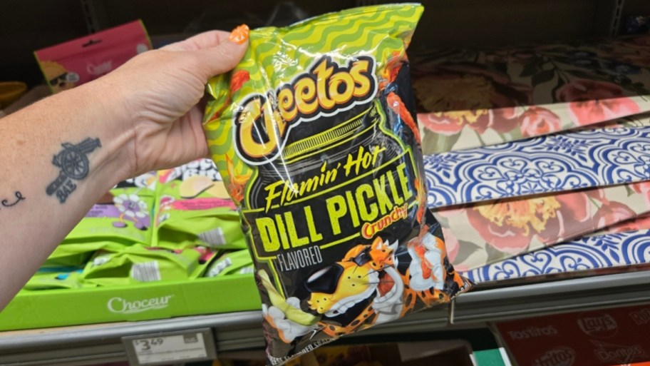 a hand holding a bag of cheetos