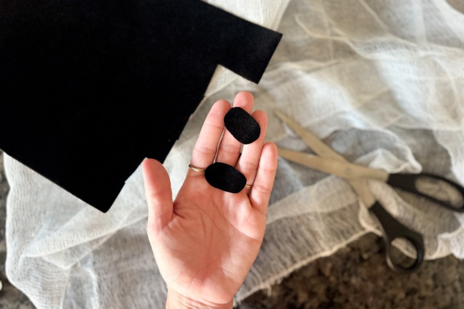 hand holding two black felt circles